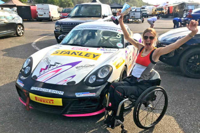 Nathalie in her wheelchair next to a race car